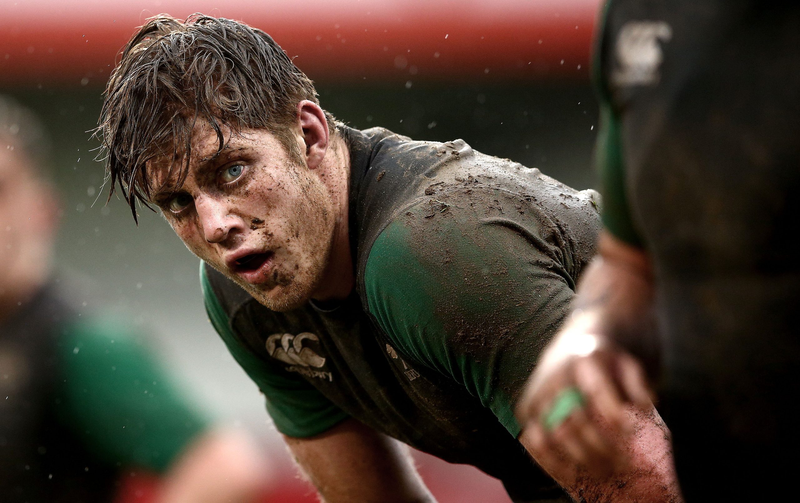 Peter Claffey covered in mud during a rugby match, wearing kit and looking exhausted after intense play.