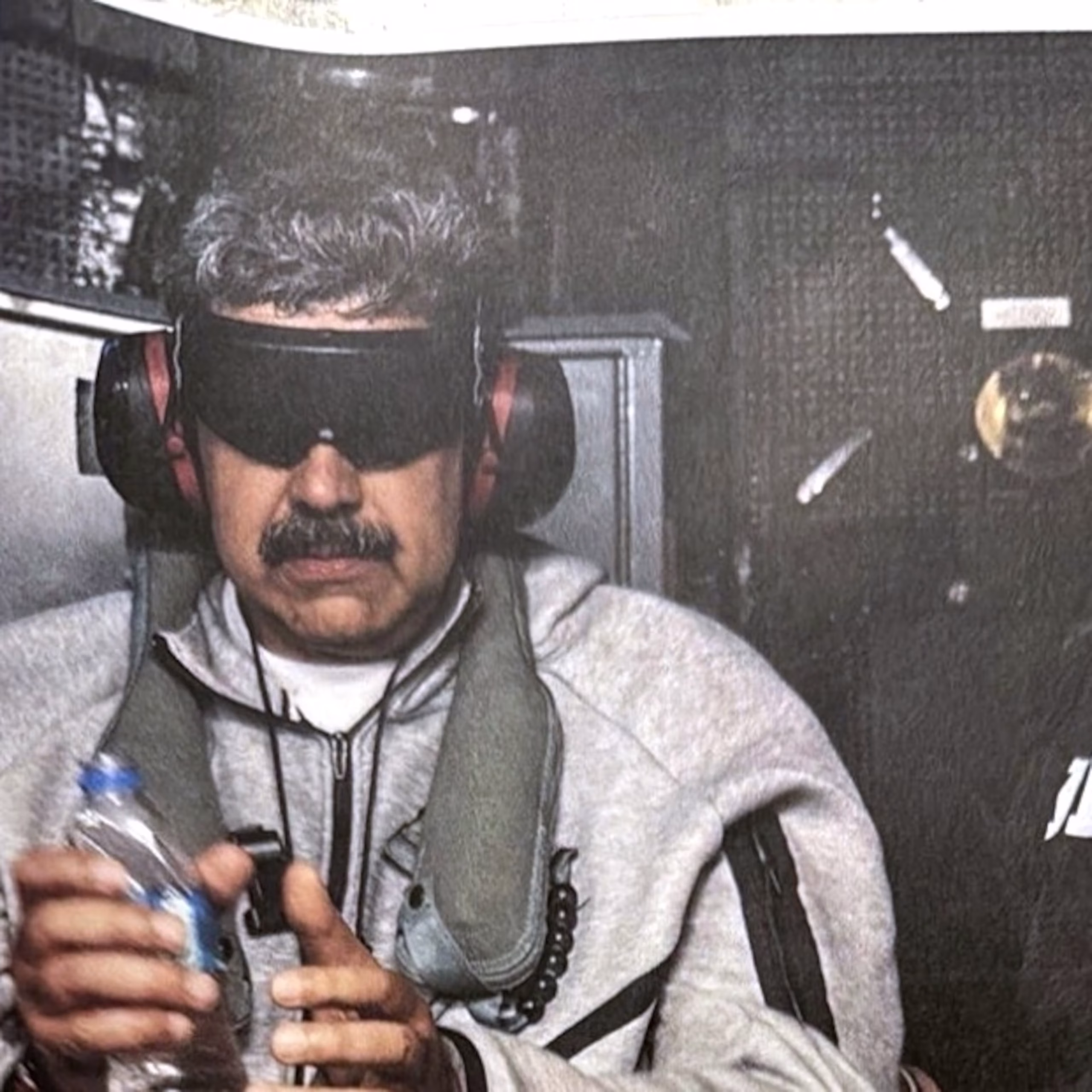 Nicolás Maduro in custody aboard a U.S. warship, flanked by armed military personnel on the deck following his capture.