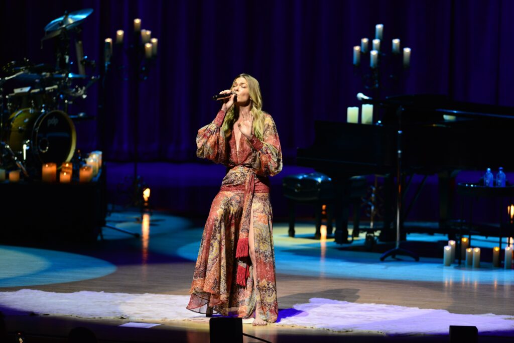 LeAnn Rimes performs passionately on stage, singing into a microphone with energy and emotion.