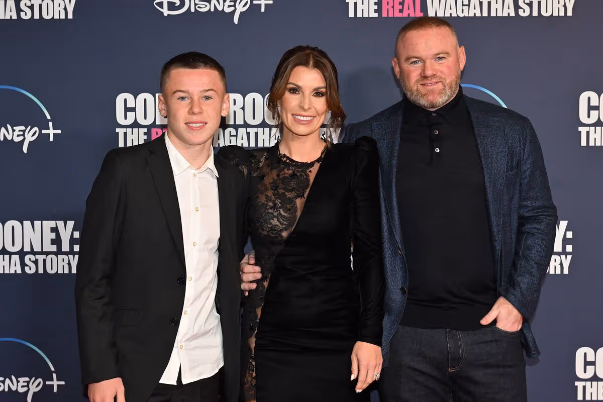 Kai Rooney smiling with parents Wayne and Coleen Rooney on the red carpet, dressed smartly for the event.