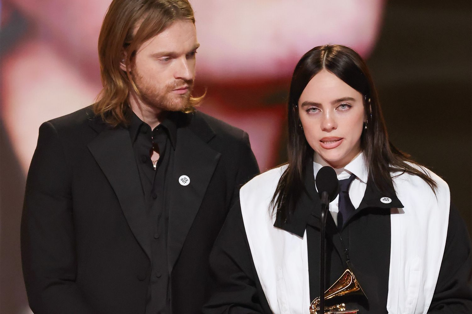 Billie Eilish and her brother Finneas onstage accepting a Grammy Award moments before her speech criticizing immigration enforcement and referencing “stolen land.”