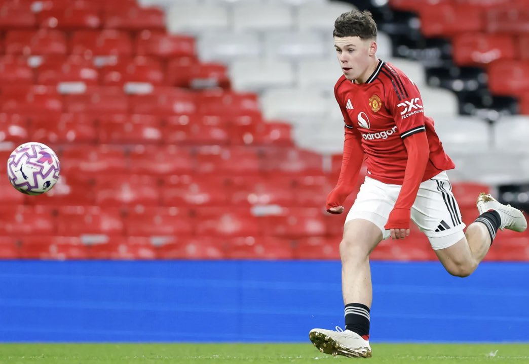 Kai Rooney sprinting with the ball during a youth match at Old Trafford, wearing Manchester United colors.