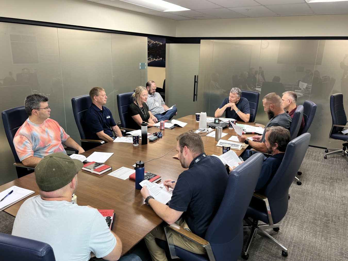 Office team meeting showing diverse employees engaged and multitasking, reflecting corporate team dynamics.