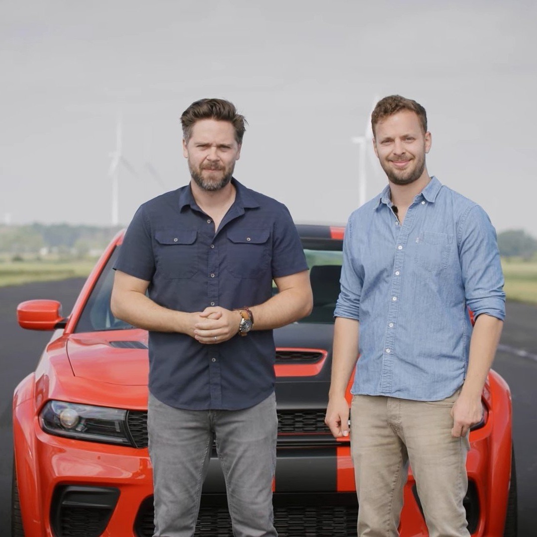 Thomas Holland and James Engelsman stand in front of a car on the set of their YouTube show Throttle House, showcasing their passion for cars and motoring content