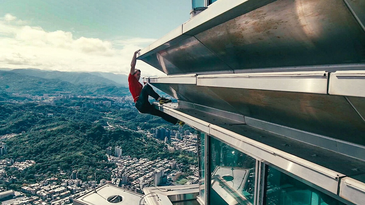Alex Honnold hangs from the exterior of Taipei 101 during a high-rise climb above the city.