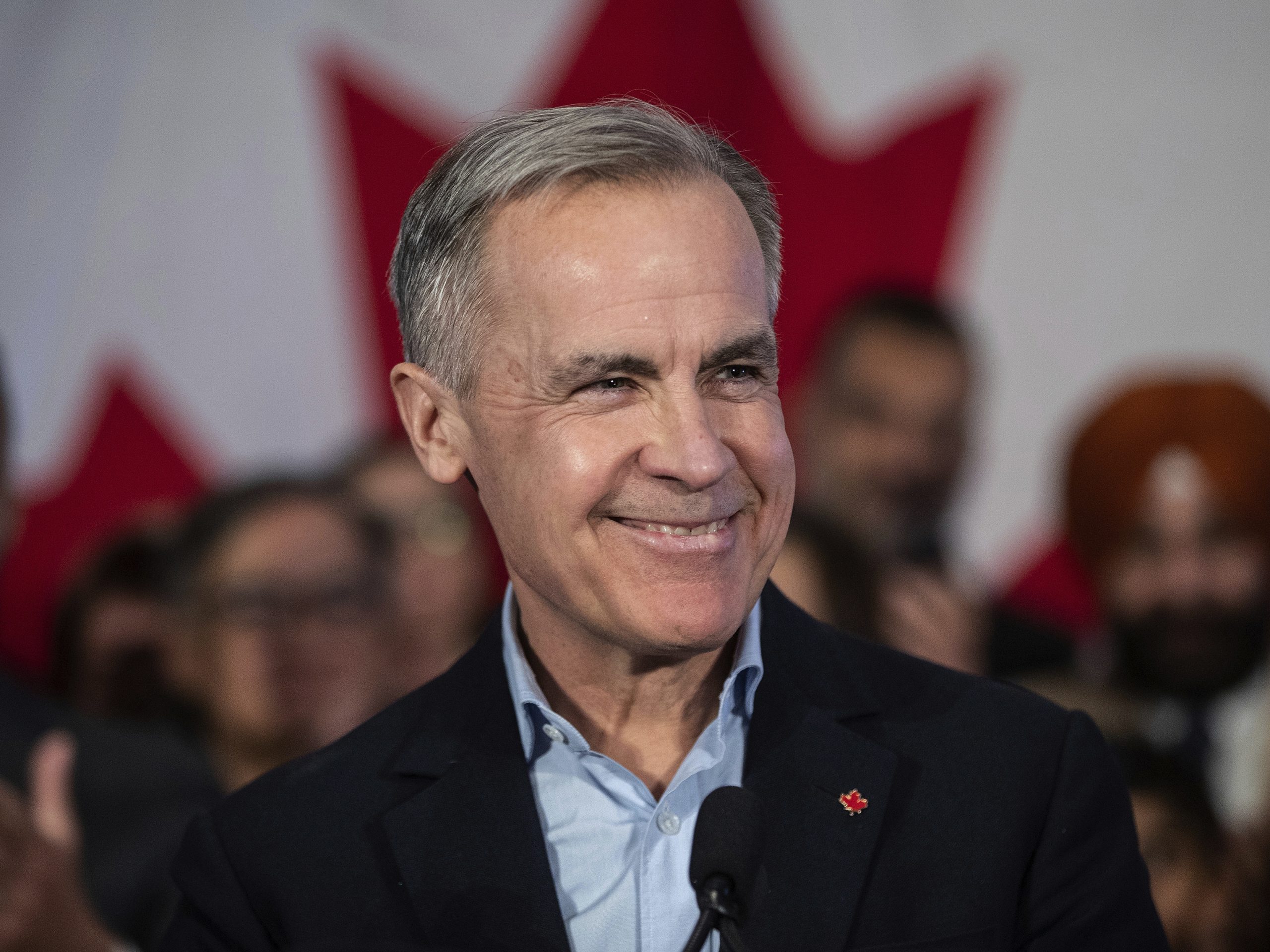 Canadian Prime Minister Mark Carney smiling and speaking to an engaged crowd, promoting confidence in Canada’s auto industry plans.