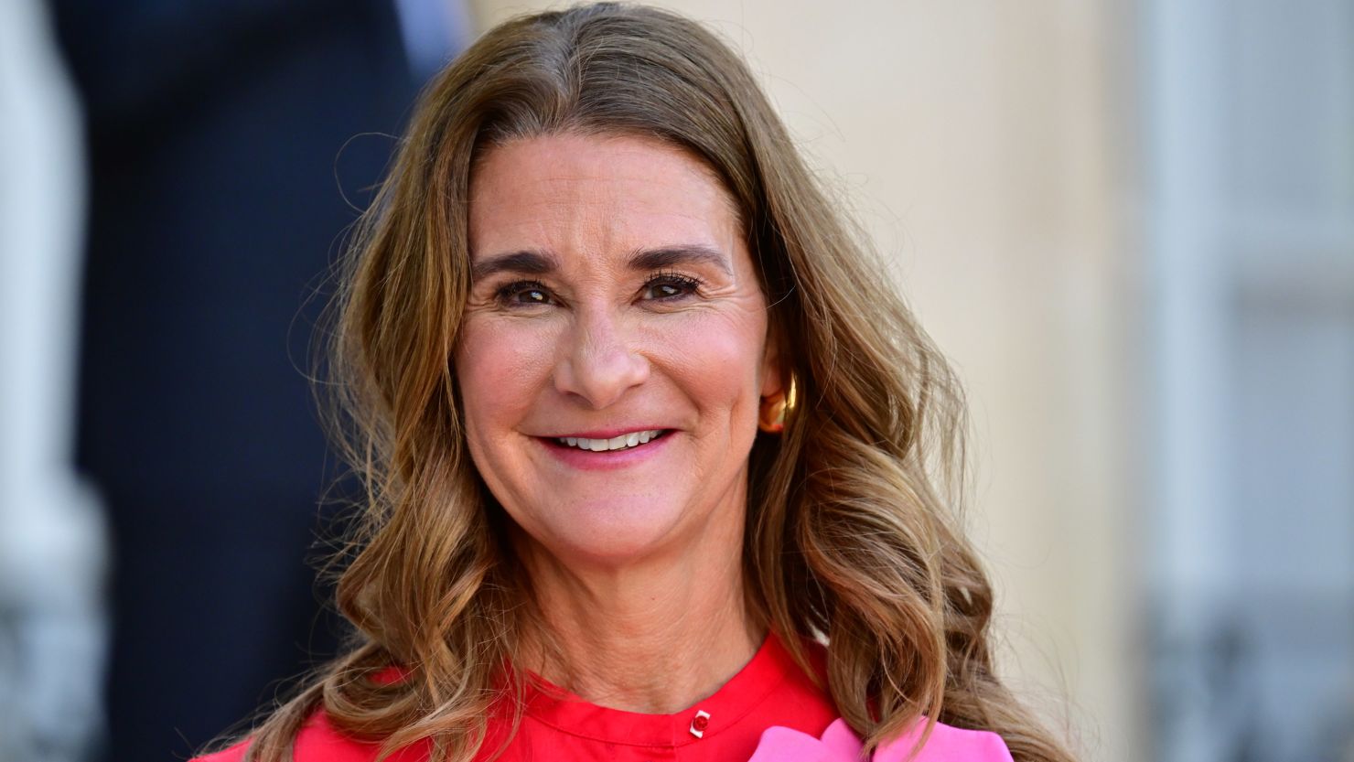 Melinda French Gates attending a public event, smiling, wearing a red dress