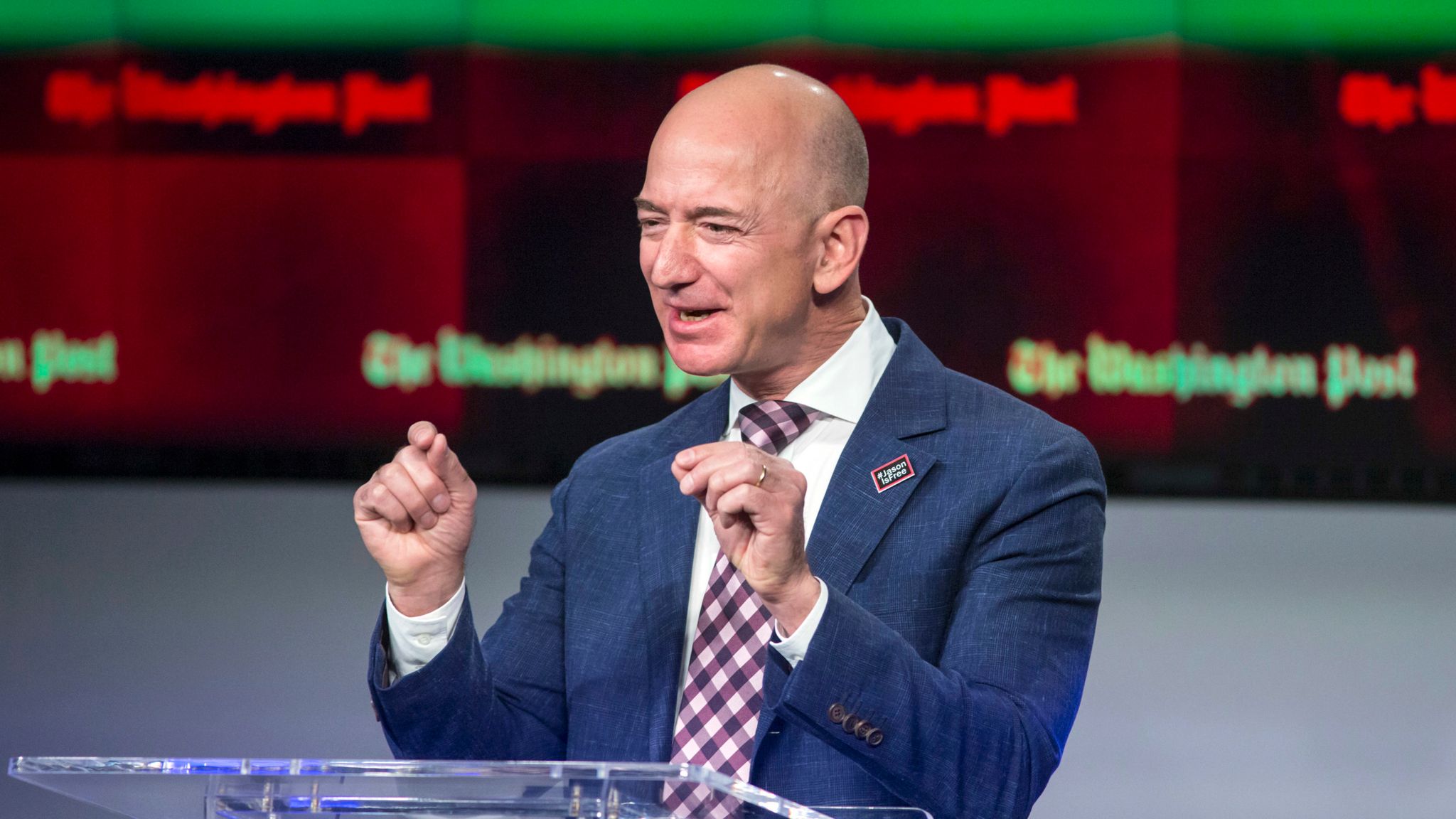 Jeff Bezos speaking at a podium during a public event, highlighting his role in The Washington Post’s recent newsroom layoffs.