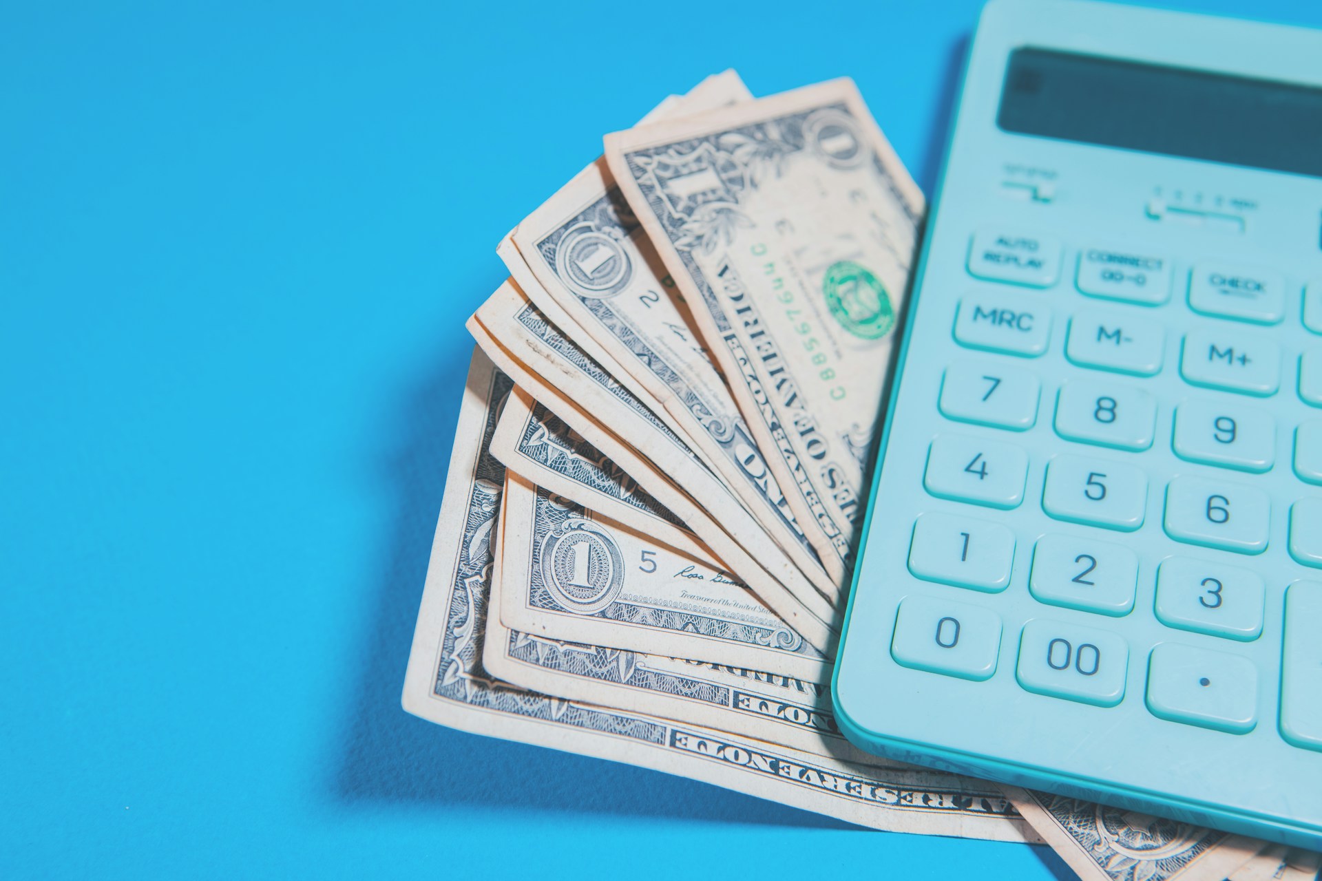 Us dollar bills and a calculator on blue background