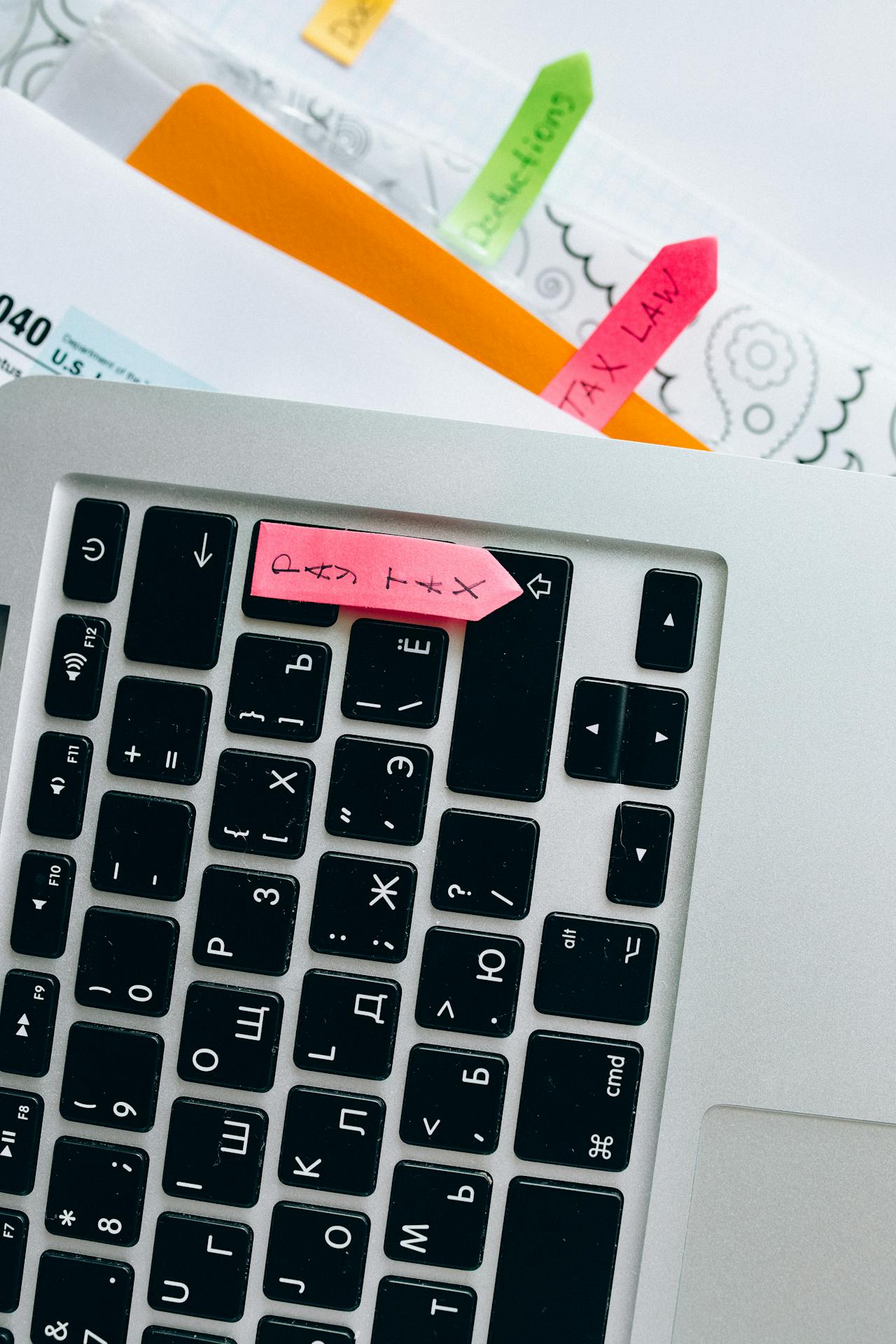 Laptop with tax documents featuring highlighted sticky notes for organization and reminders.