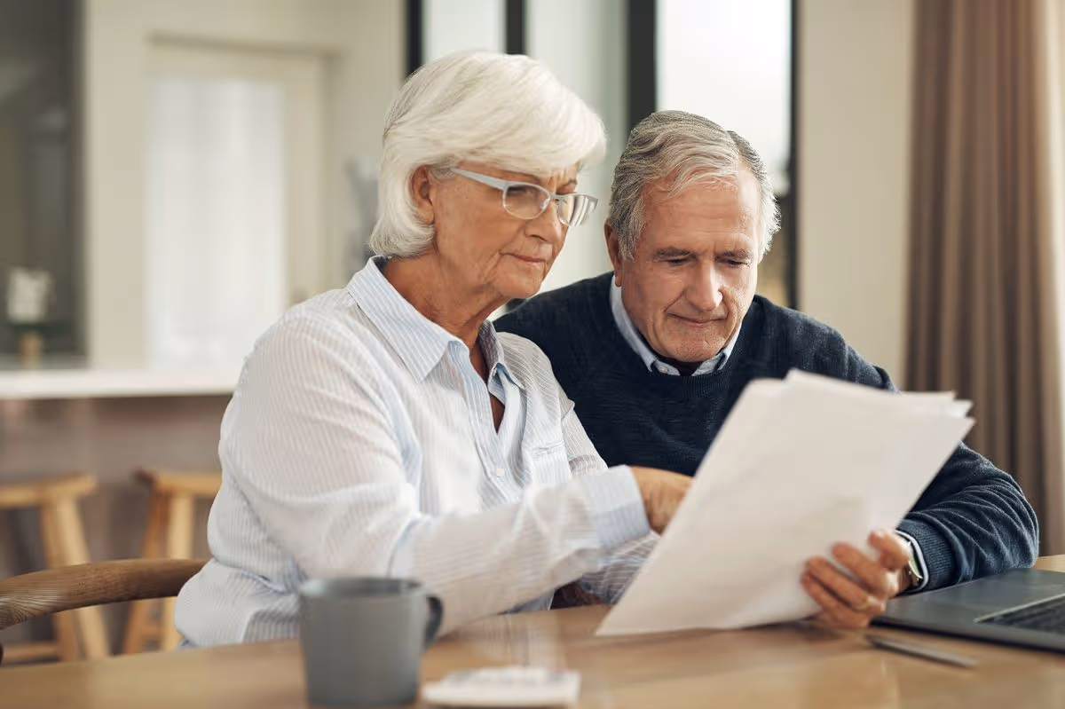 Retired couple examining pension documents while discussing household finances.
