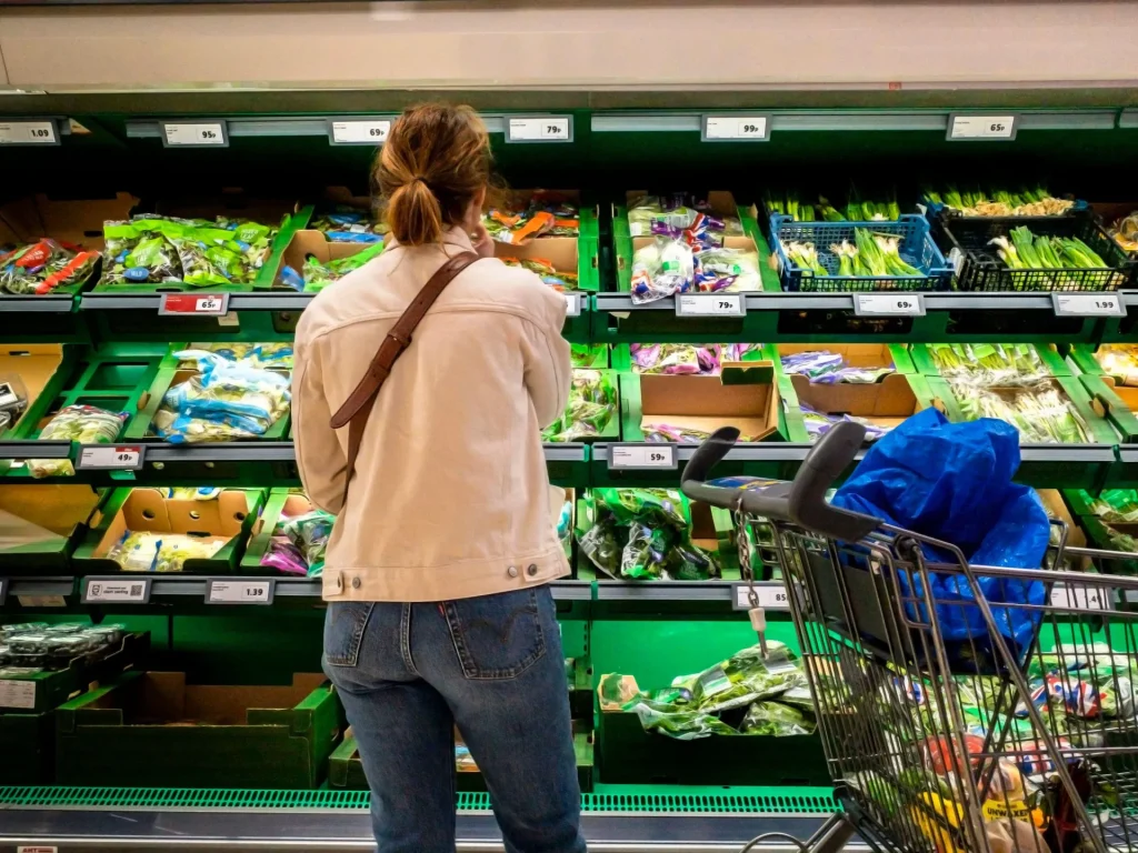 Shoppers comparing branded and private-label food products in a supermarket aisle